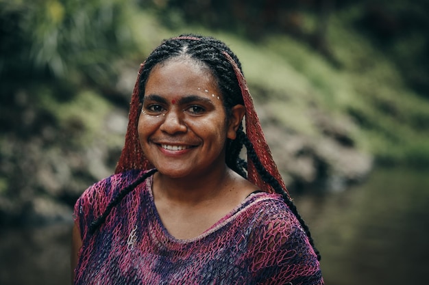 Papua woman of Dani tribe in traditional clothes against river background