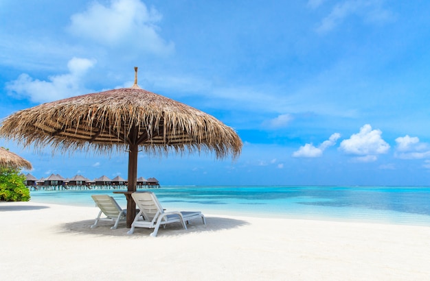 Paradise beach with sunloungers and straw umbrella