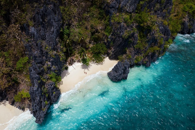 Paradisiacal beach with turquoise waters and a couple enjoying alone on an island in the Philippines