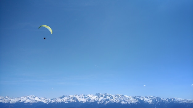 Paraglider in the blue sky of mountains