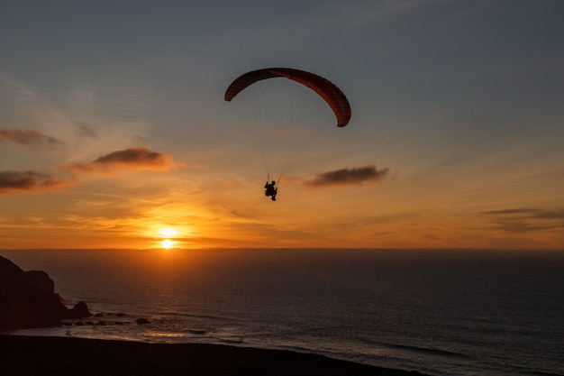 Paraglider flying over thesea shore at sunset. Paragliding sport