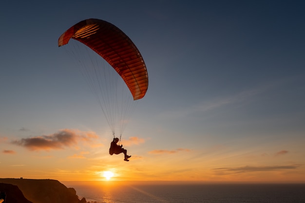 Paraglider flying over thesea shore at sunset. Paragliding sport