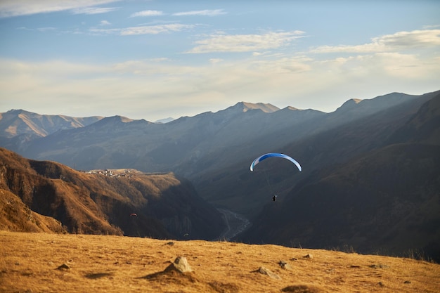 Paraglider silhouette flying over above hills caucasus mountains on a sunny day beauty world svaneti...