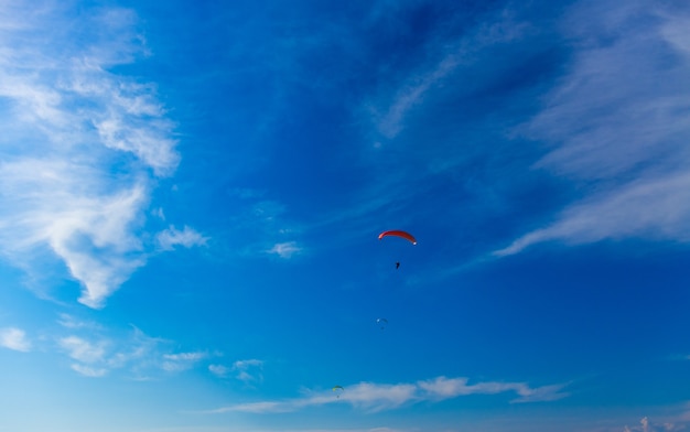 Paragliding in blue sky. Parachute with paraglider is flying. Extreme sports, freedom concept