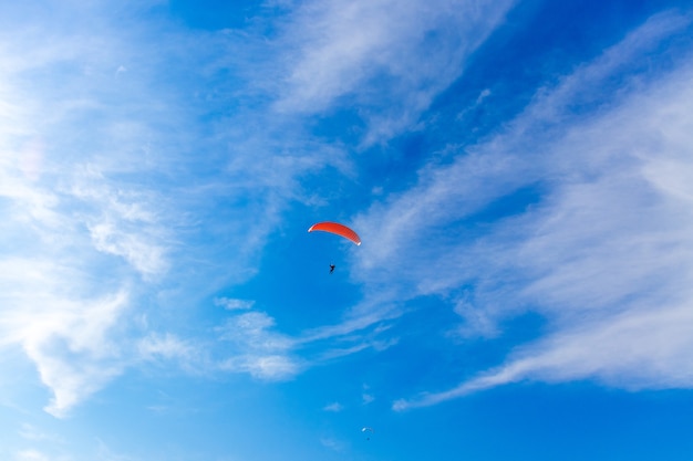 Paragliding in blue sky. Parachute with paraglider is flying. Extreme sports, freedom concept