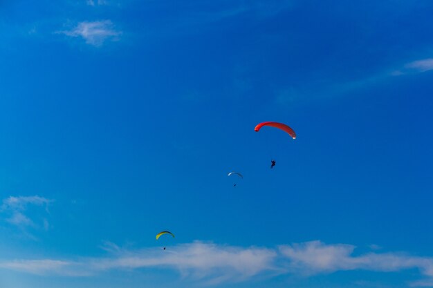 Paragliding in blue sky. Parachute with paraglider is flying. Extreme sports, freedom concept