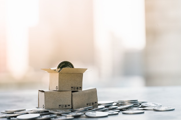 Parcel box on pile of coins with city backgrounds.