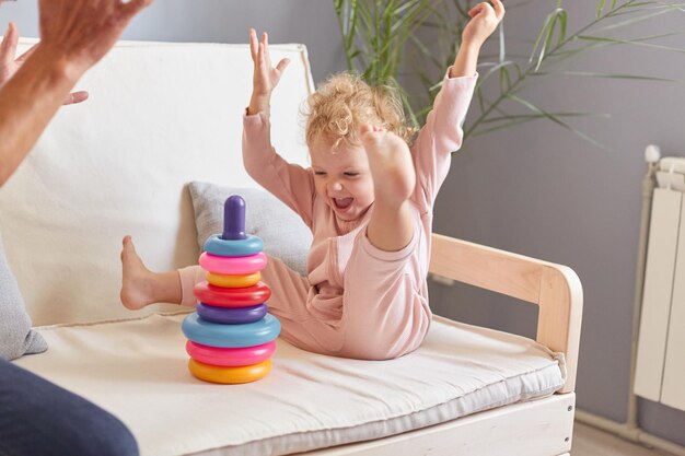 Parent and child interaction Educational time with grandpa Toddler's playful game Unrecognizable man playing toy with toddler granddaughter on sofa in living room