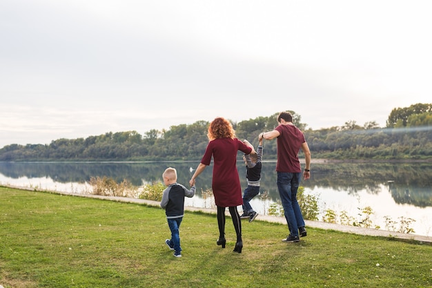 Parent, childhood and nature concept - Family playing with two sons by the water.