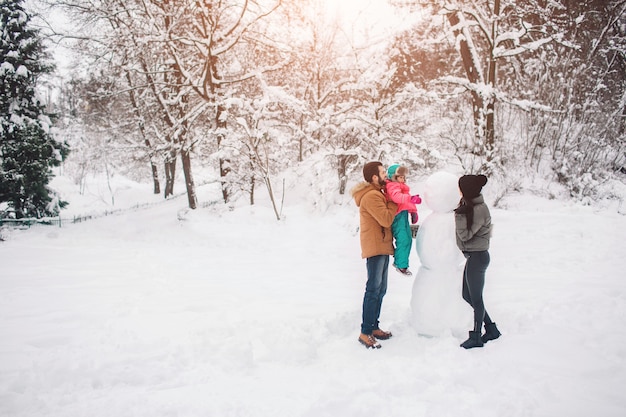 Parenthood, fashion, season and people concept - happy family with child in winter clothes outdoors