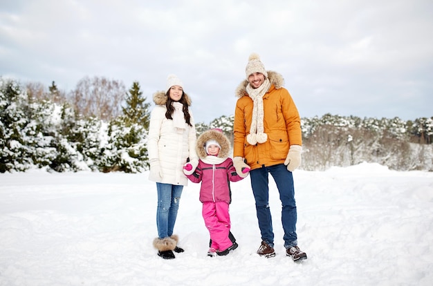 parenthood, fashion, season and people concept - happy family with child in winter clothes outdoors