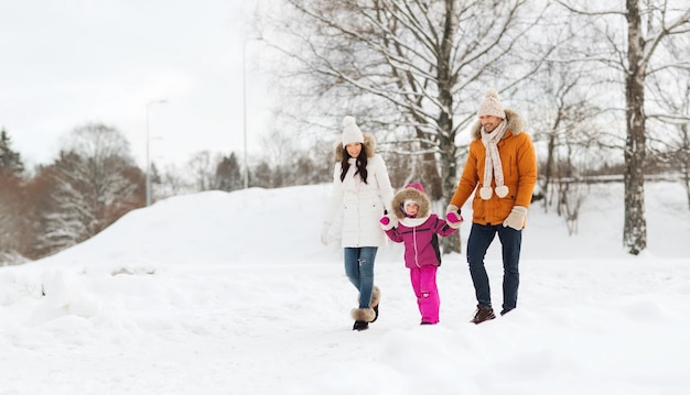 parenthood, fashion, season and people concept - happy family with child in winter clothes walking outdoors