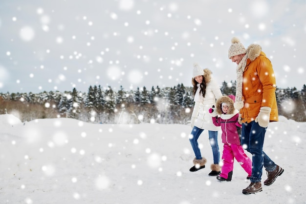 parenthood, fashion, season and people concept - happy family with child in winter clothes walking outdoors