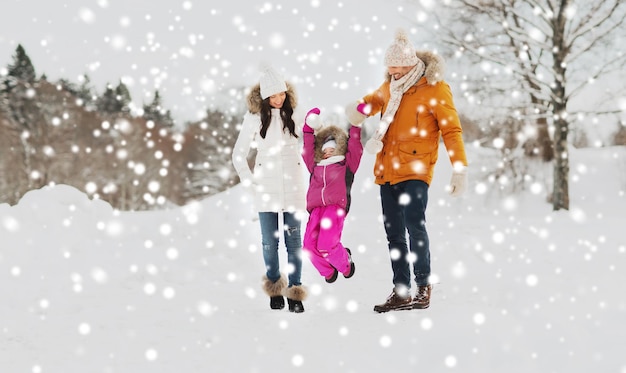 parenthood, fashion, season and people concept - happy family with child in winter clothes walking outdoors