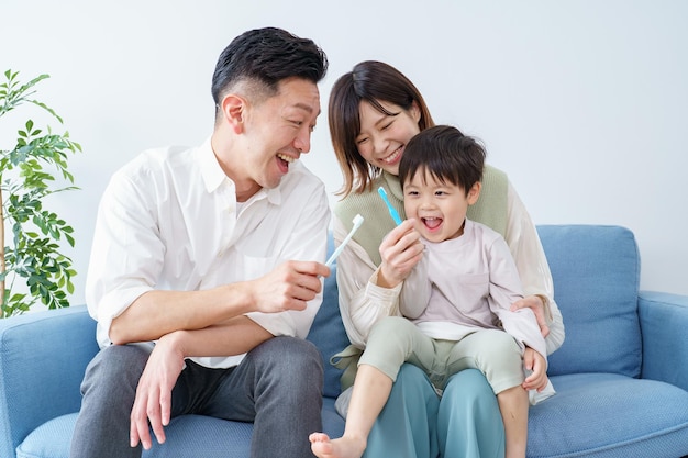 Parents and child brushing teeth on the sofa