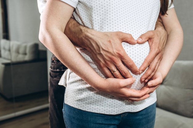 Parents hands making a heart on the belly of the pregnant mother