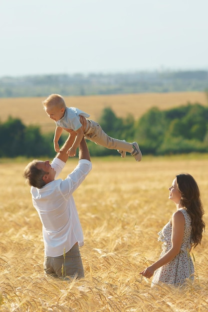 Parents happiness father playing with son on the wheat field Family walking with child outdoor