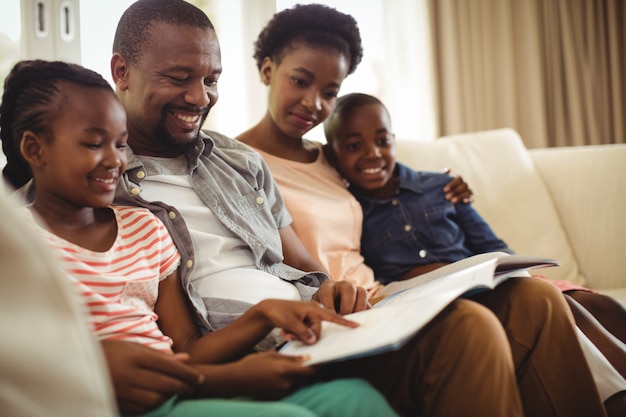 Parents and kids sitting together on sofa with photo album