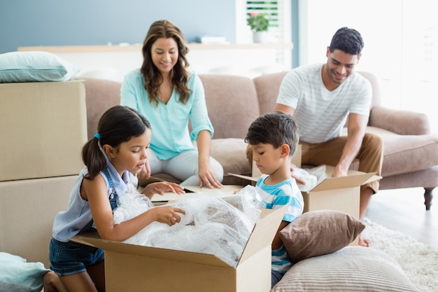 Parents and kids unpacking carton boxes in living room