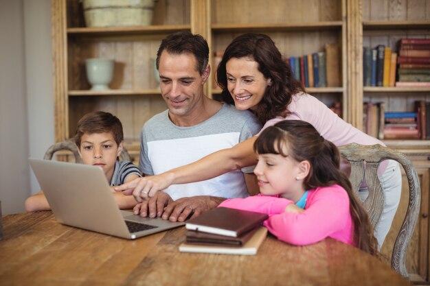 Parents and kids using laptop on table in study room