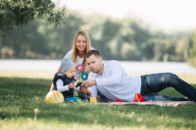 Parents play with their little son sitting on the grass