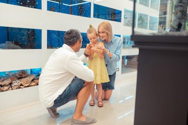 Parents standing near daughter holding and looking at hamster