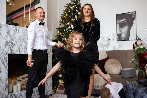 Parents and their happy children playing with confetti on Christmas at home