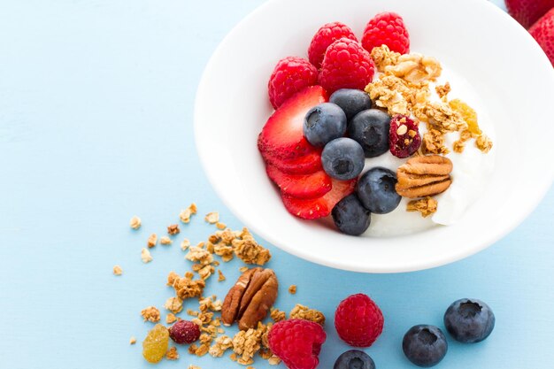 Parfait with fresh fruits and granola in white bowl.