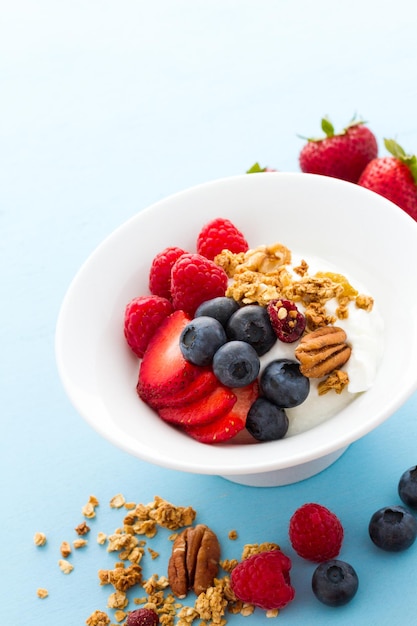 Parfait with fresh fruits and granola in white bowl.