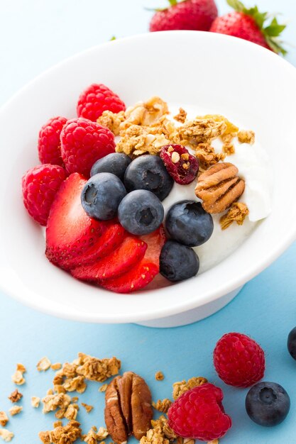 Parfait with fresh fruits and granola in white bowl.