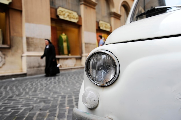 A parked Fiat 500 in the streets of Rome a nun walking on the background The Fiat 500 Cinquecento is a famous Italian symbol