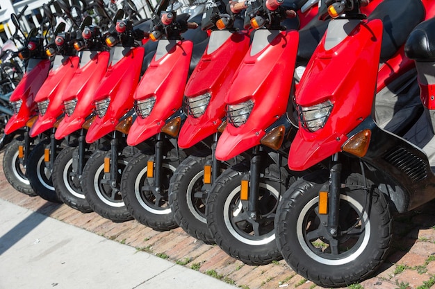 Parked rental moped in row with tire parked rental moped red color parked rental moped