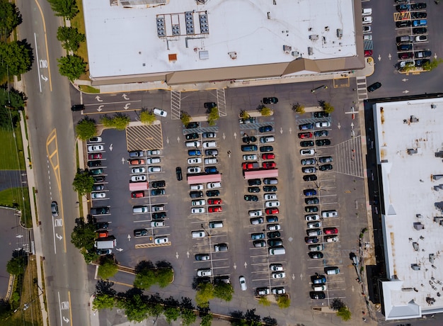 The Parking lot is almost completely filled with colorful cars near on shopping center from the height of bird flight.