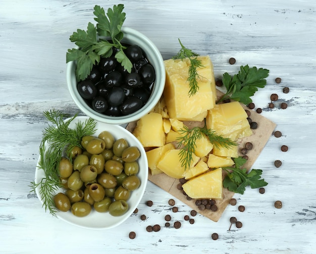 Parmesan cheese fresh herbs and olives on wooden background