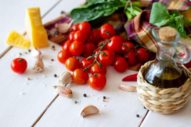 Parmesan, tomatoes, olive oil and other ingredients for salad dressing. White background.