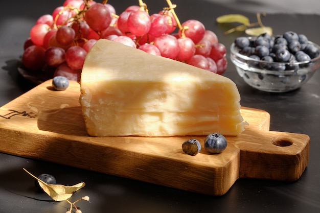 Parmigiano Cheese on wooden cut board with grape berries