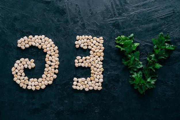 Parsley and dry garbanzo in form of letters meaning veg vegetarian isolated over dark background Organic protein product Vegan food