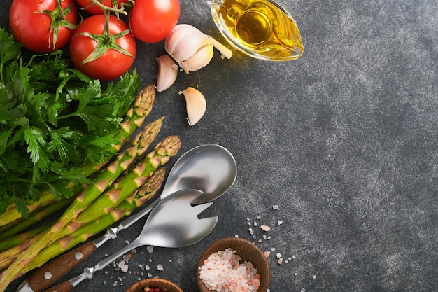 Parsley parsley tomato garlic olive oil pepper salt and salad fork and spoon on Black stone cooking background Food cooking background Ingredients for cooking food background Mock up