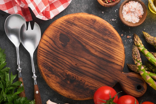 Parsley parsley tomato garlic olive oil pepper salt wooden stand and salad fork and spoon on black stone background Food cooking background Ingredients for cooking food background Mock up