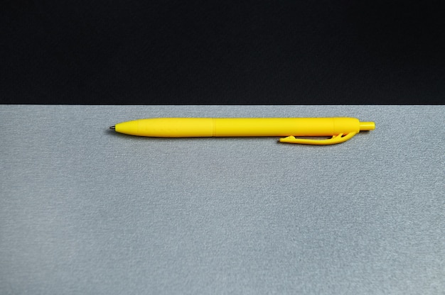 A part of black sheet of paper and a yellow pen on a gray background. flat lay, top view, copy space