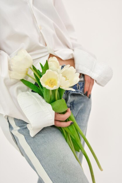 Photo part of the body of a girl who holds white tulips valentine concept