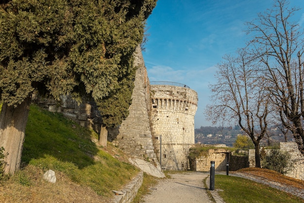 Part of the castle of the city of Brescia on a sunny winter day. A view on the tower. Castello di Brescia, Lombardy, Italy. Medieval castle with battlements, a tower, drawbridge and ramparts.