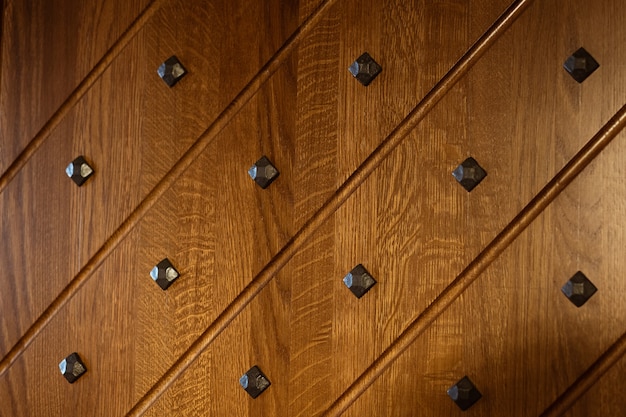 Part of the decorative wooden surface decorated with black metal rivets and diagonal lines shot by