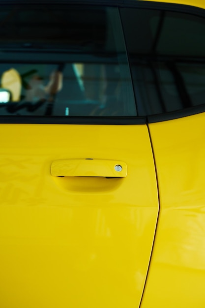 Part of door and window of modern electric car of yellow color