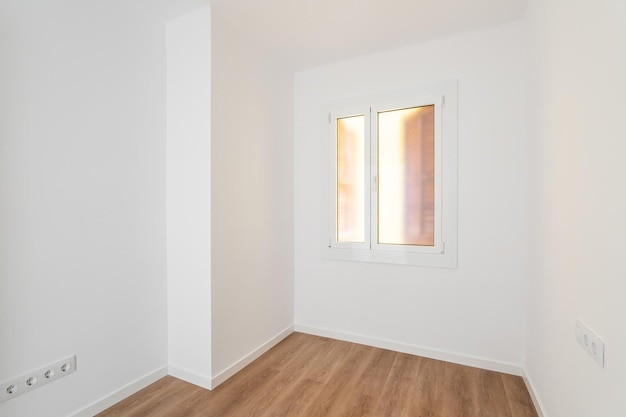 Part of an empty room with white walls brown parquet plastic window in wall with frosted translucent