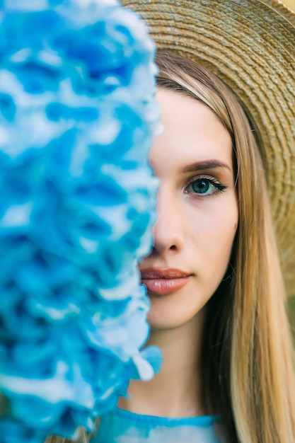 Part of face. Portrait of young pretty woman in straw hat with half face near hydragea flower.