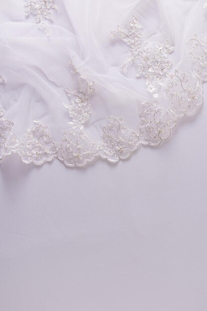 Photo part of lace embroidered tulle fabric on a white satin background vertical view a copy space layout for wedding design