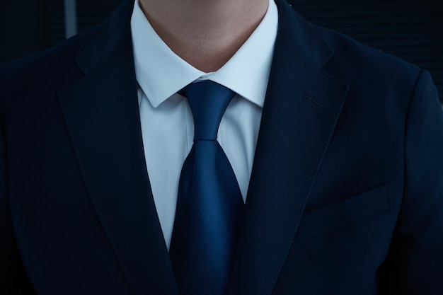 Part of man body side folded his arms in black suit on black background business concept