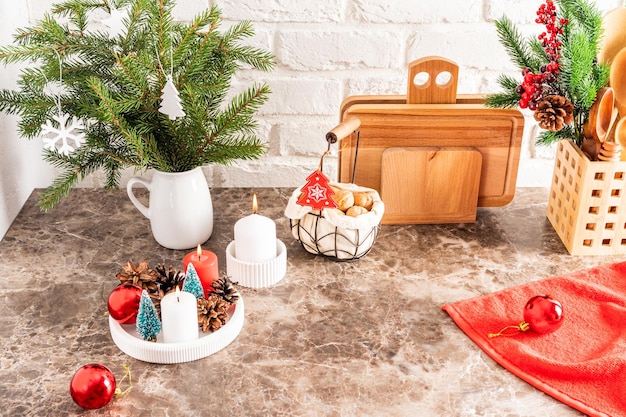 Part of a marble countertop in the kitchen with a bouquet of spruce branches a tray with burning candles decorations for the new year and Christmas