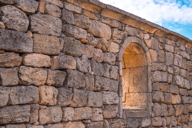 Part of an old stone wall with an arched window opening in the archaeological museum of Chersonesos